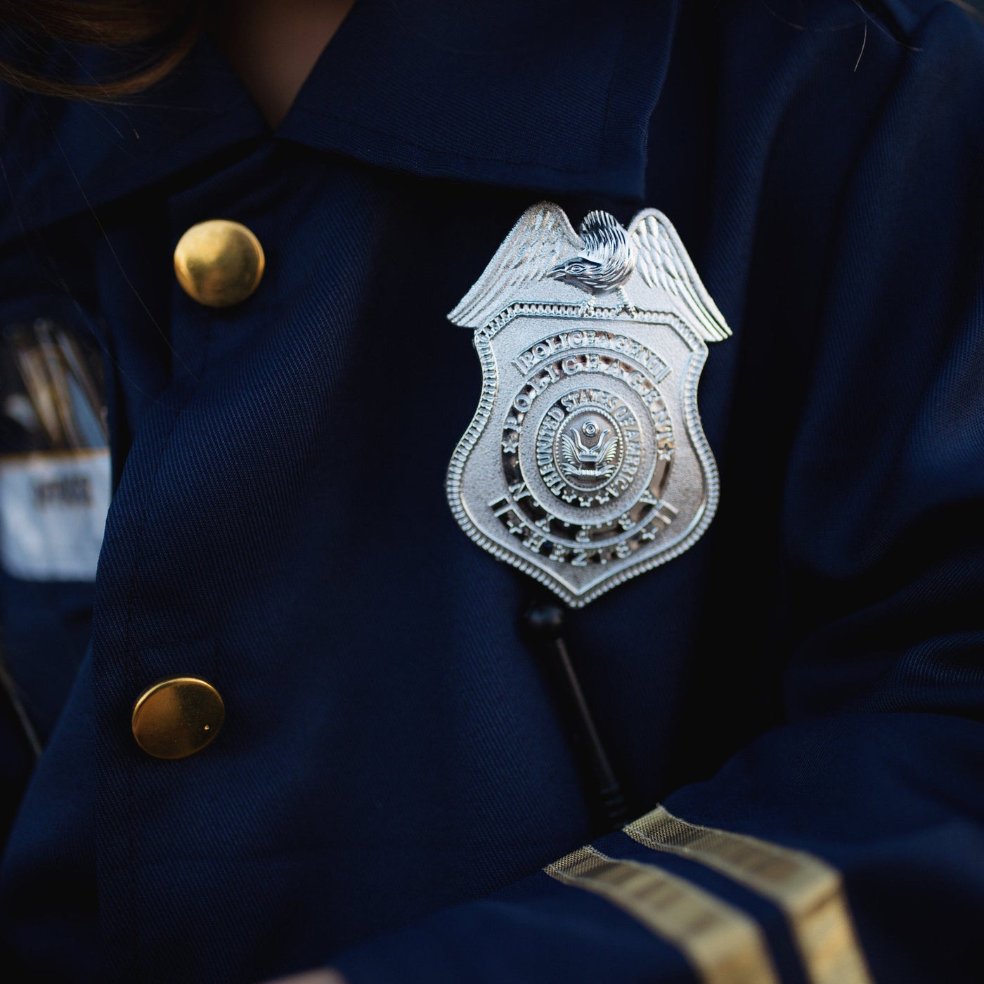 Pige iført politibetjent sæt fra Great Pretenders - zoom på politiskilt
