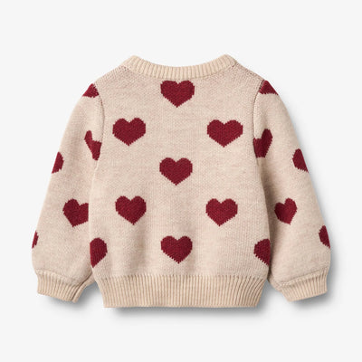 Jaquard Cardigan, Hearts, OffWhite, Merino Wool fra Wheat

Denne langærmede strikcardigan til børn er strikket i en dejlig blød uldkvalitet og har en behagelig, normal til let løs pasform. 